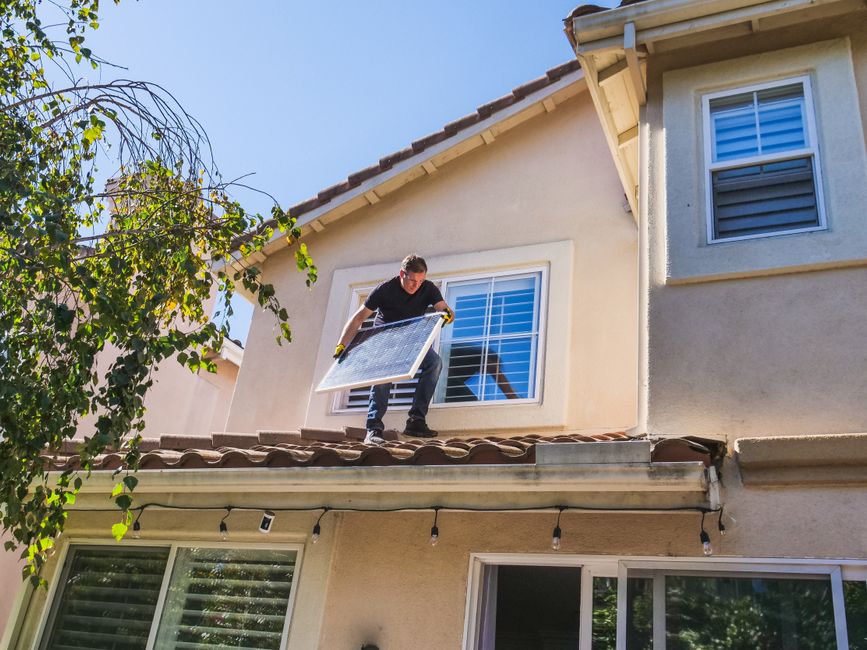 Worker on a ladder at the exterior wall of a house.