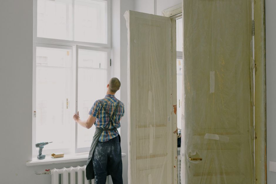 Worker in an apron fitting a window frame into a wall opening.